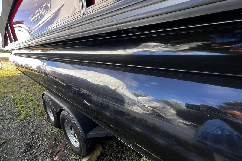 Slide: The Image of 2023 Regency 250 DL3 boat on trailer, glossy black exterior, parked on grass. - 27