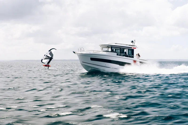Slide: The Image of 2026 Jeanneau NC 895 Sport Series 2 cruising alongside a wing surfer on open water. - 1