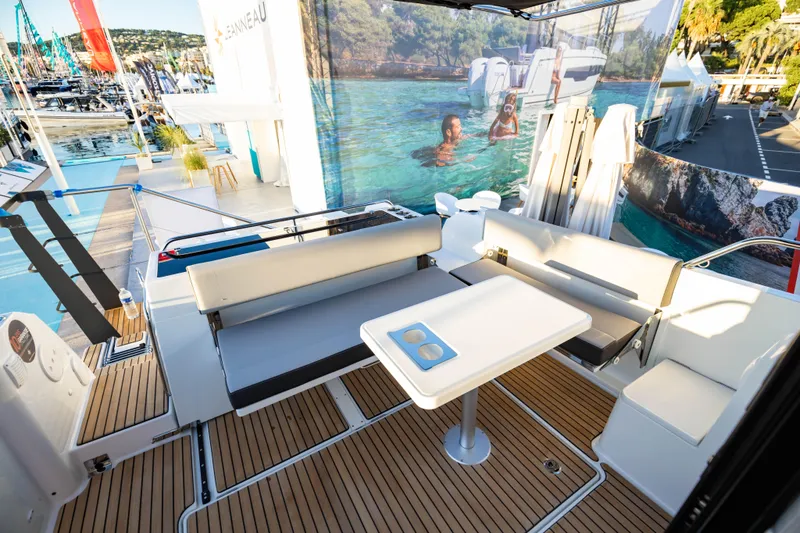 Slide: The Image of 2026 Jeanneau NC 895 Sport Series 2 boat interior with seating and table, docked at marina. - 14