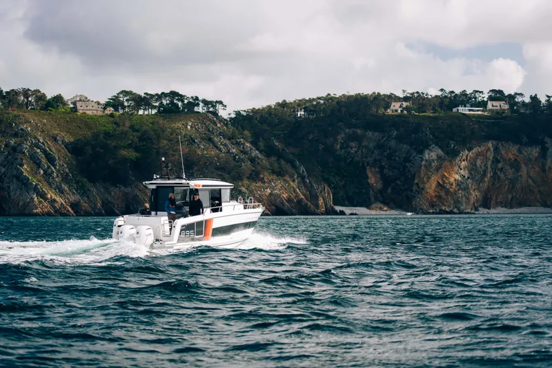 Slide: The Image of 2026 Jeanneau NC 895 Sport Series 2 cruising near rocky coastline under cloudy sky. - 5