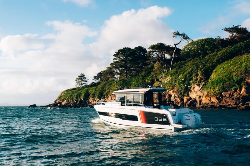 Slide: The Image of 2026 Jeanneau NC 895 Sport Series 2 cruising near a scenic, rocky coastline. - 7