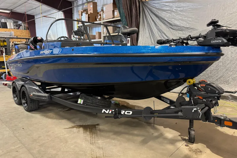 Slide: The Image of 2026 Nitro ZV20 Sport Pro boat in a garage, featuring a blue hull and Garmin equipment. - 2