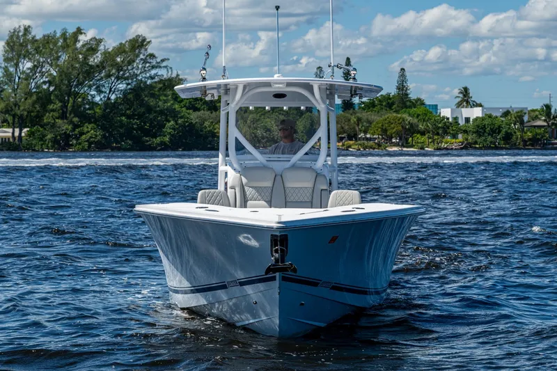 Slide: The Image of 2022 Jupiter 32 boat cruising on a sunny day with lush greenery in the background. - 28