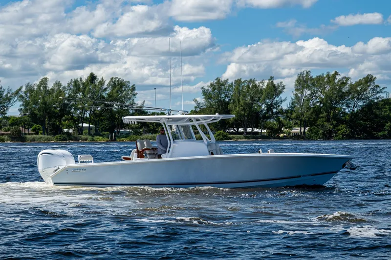 Slide: The Image of 2022 Jupiter 32 boat cruising on a sunny day with trees in the background. - 29