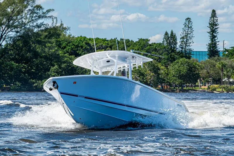 Slide: The Image of 2022 Jupiter 32 boat cruising on a sunny day with lush greenery in the background. - 31
