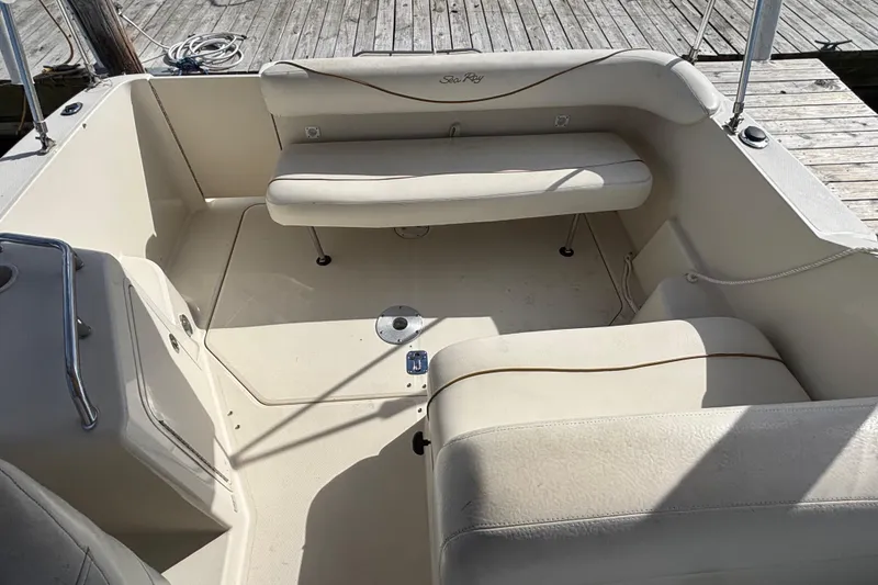 Slide: The Image of 2000 Sea Ray 240 Sundancer boat interior with beige seating and wooden dock background. - 5