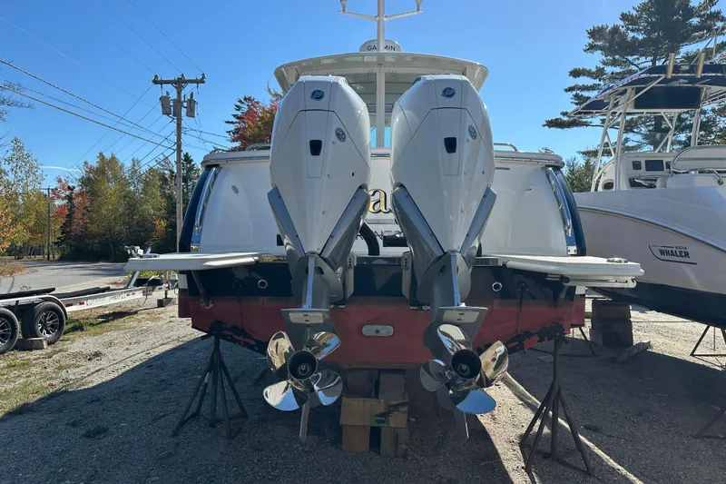 Slide: The Image of 2024 Back Cove 34O boat with striped seating and table, docked near other boats. - 16