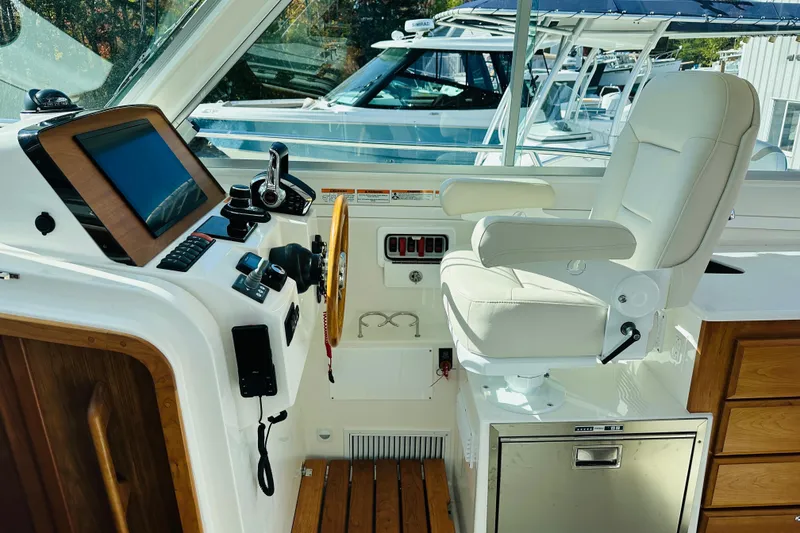 Slide: The Image of 2024 Back Cove 34O boat with striped seating and table, docked near other boats. - 4