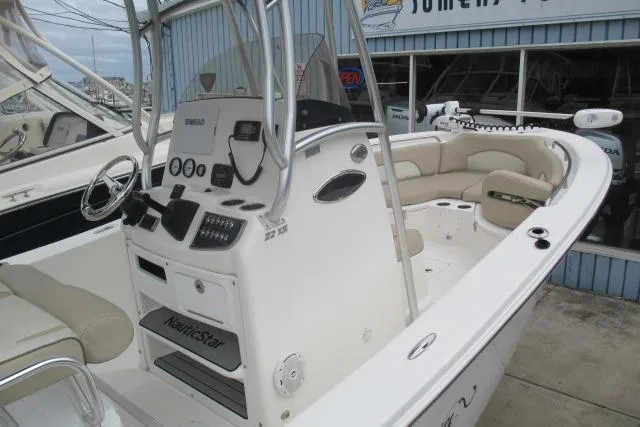 Slide: The Image of 2018 NauticStar 22 XS Offshore boat with center console and seating, docked at marina. - 2