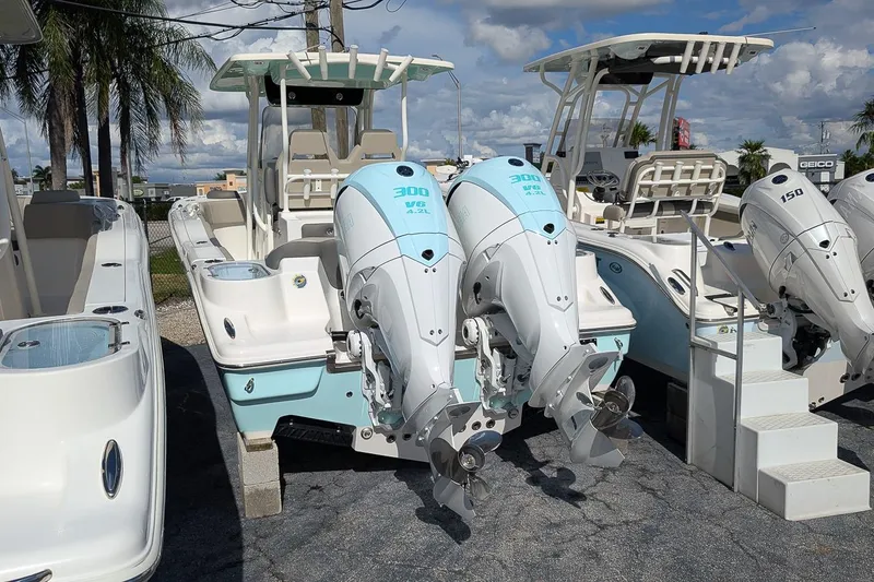 Slide: The Image of 2025 Key West 263 FS boat with dual 300 HP engines, docked under a sunny sky. - 2