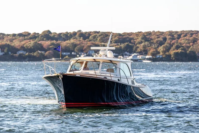 Slide: The Image of 2007 Hinckley Talaria 40 yacht cruising on scenic waters with autumn foliage backdrop. - 2