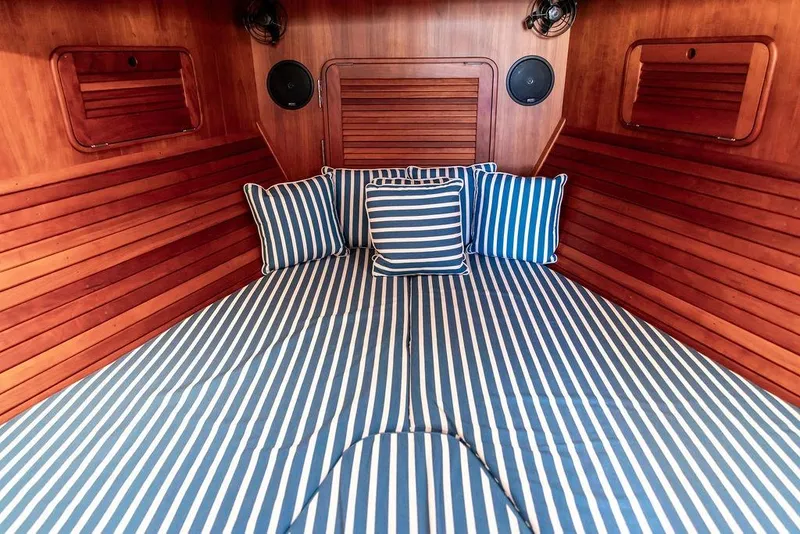 Slide: The Image of Interior cabin of 2007 Hinckley Talaria 40 with striped bedding and wooden paneling. - 26