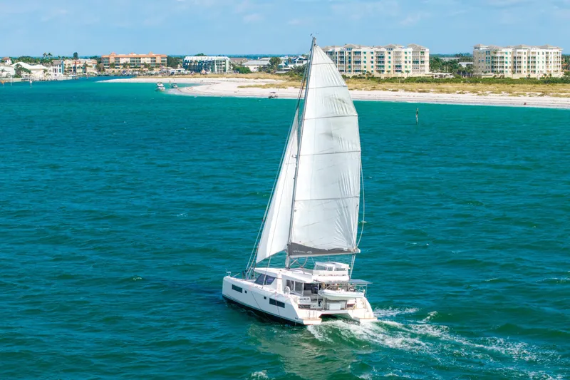 The Image of Sailing catamaran Leopard 45, 2021 model, cruising in turquoise waters near a coastal city. - 1