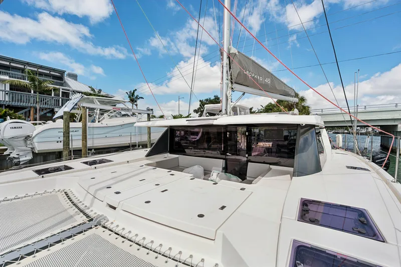 Slide: The Image of 2021 Leopard 45 catamaran docked, showcasing sleek design and spacious deck under blue skies. - 11