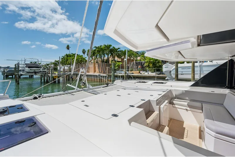 Slide: The Image of 2021 Leopard 45 catamaran docked, featuring spacious deck and seating area under clear skies. - 5
