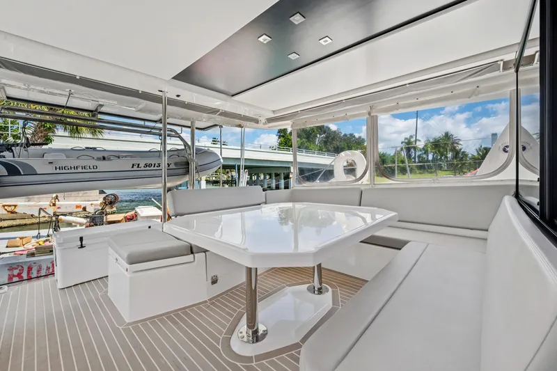 Slide: The Image of Luxurious 2021 Leopard 45 yacht interior with sleek seating and table, docked near a scenic waterfront. - 50