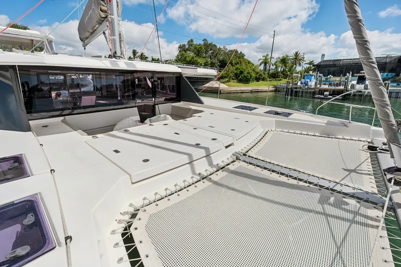 Slide: The Image of 2021 Leopard 45 catamaran with spacious deck and netting, docked in a scenic marina. - 9
