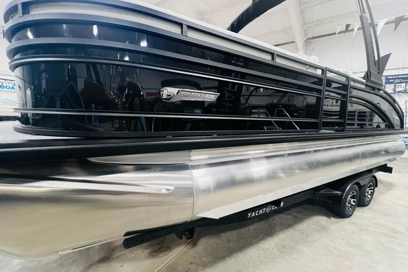 Slide: The Image of 2025 Harris Solstice 250 pontoon boat in showroom, sleek black and silver design. - 5