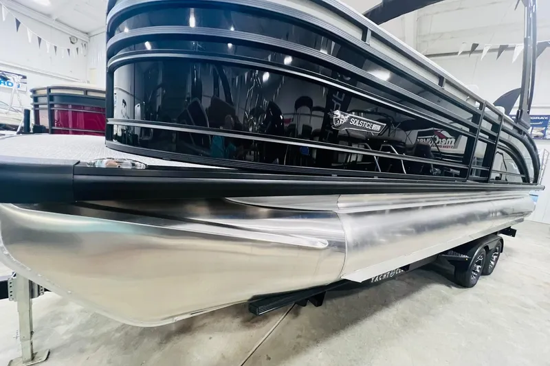 Slide: The Image of 2025 Harris Solstice 250 pontoon boat in showroom, featuring sleek black and silver design. - 58