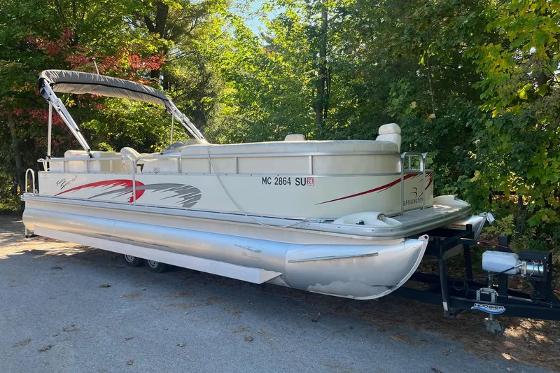 Slide: The Image of 2026 Bennington 2575 RLX pontoon boat on trailer, surrounded by lush green trees. - 3