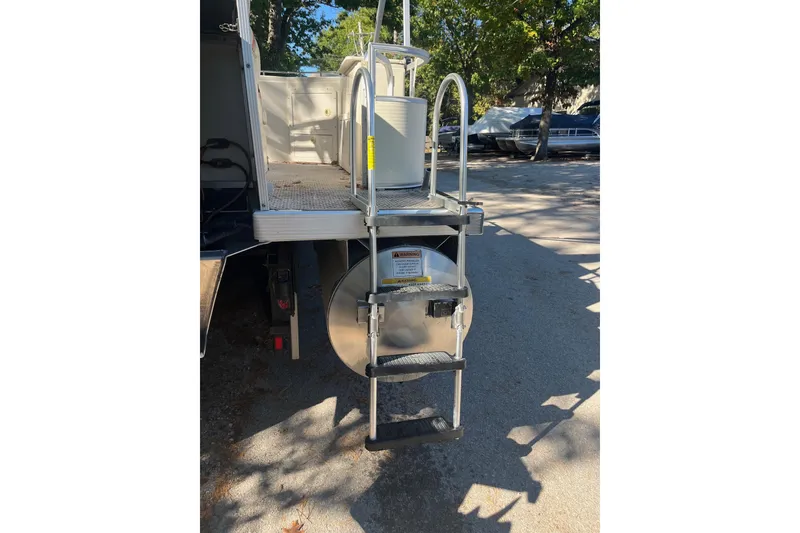 Slide: The Image of 2026 Bennington 2575 RLX boat ladder and deck, parked outdoors. - 5