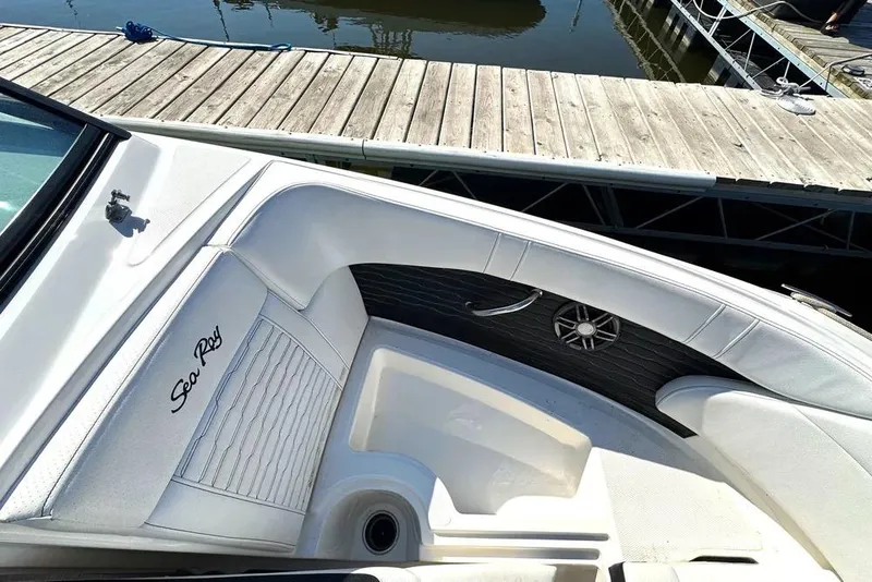 Slide: The Image of 2022 Sea Ray SPX 230 Outboard boat interior with white seating and dock view. - 18