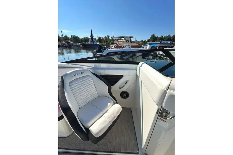 Slide: The Image of 2022 Sea Ray SPX 230 Outboard boat interior with white seating and scenic marina view. - 23
