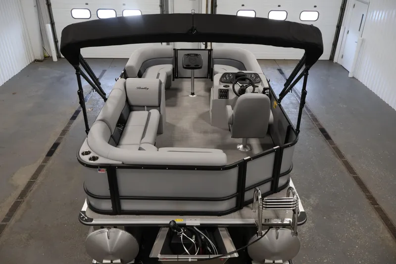 Slide: The Image of 2026 Bentley Pontoons 160 Cruise LE with sleek interior and canopy in a showroom. - 9