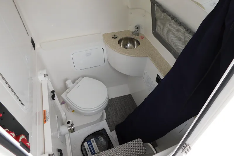 Slide: The Image of 2026 Regulator 28 boat interior with compact bathroom, featuring a toilet and sink. - 37