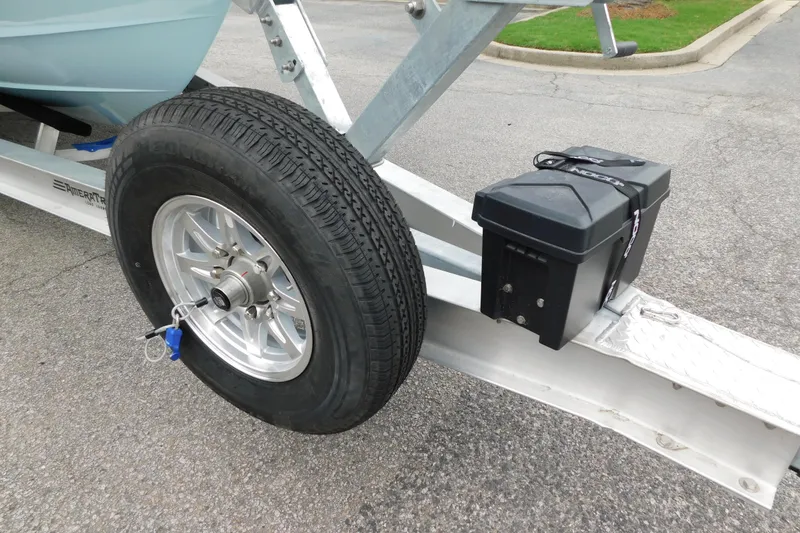 Slide: The Image of 2026 Regulator 28 boat trailer with tire and battery box on pavement. - 60