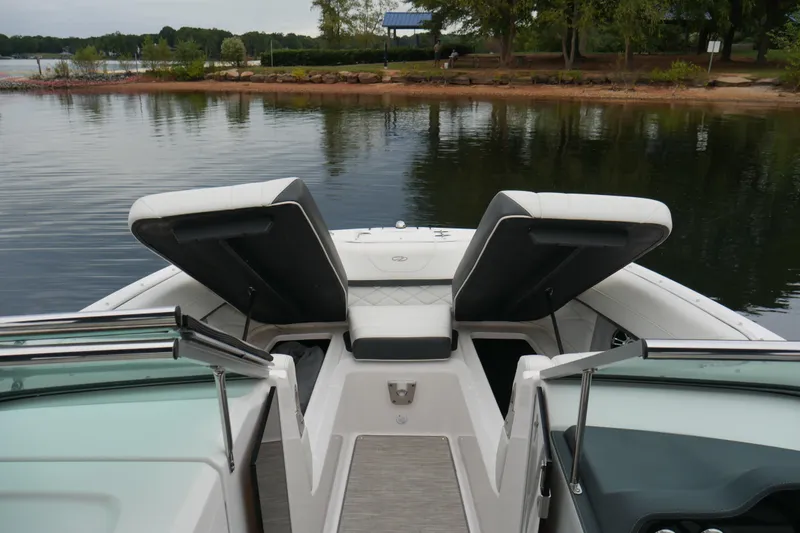 Slide: The Image of 2019 Regal 26 FasDeck boat interior with open storage compartments by a serene lake. - 24