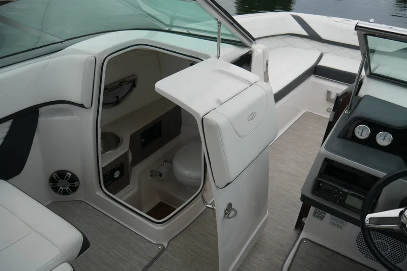 Slide: The Image of 2019 Regal 26 FasDeck boat interior with seating, helm, and compact restroom. - 27