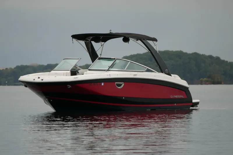 Slide: The Image of 2019 Regal 26 FasDeck boat on calm lake with forested background. - 4