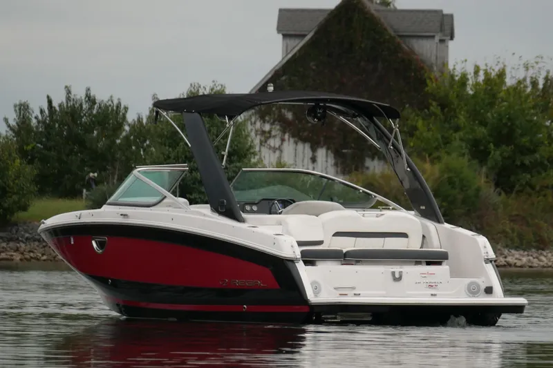 Slide: The Image of 2019 Regal 26 FasDeck boat on calm water near a rustic house. - 5