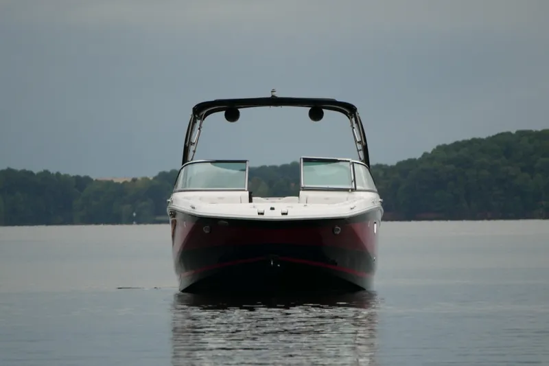 Slide: The Image of 2019 Regal 26 FasDeck boat on calm lake with forested background. - 6