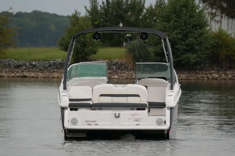 Slide: The Image of 2019 Regal 26 FasDeck boat on calm water, rear view with lush greenery background. - 7