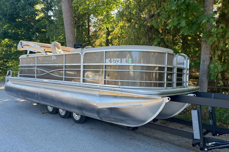 Slide: The Image of 2018 Berkshire 22 Quad Bench Tritoon on trailer, parked near trees. - 0