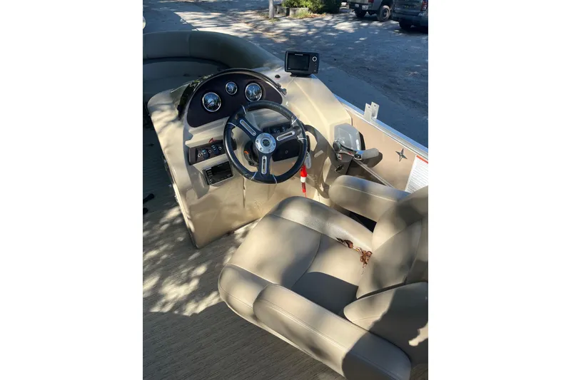 Slide: The Image of 2018 Berkshire 22 Quad Bench Tritoon steering console with beige seating and controls. - 4