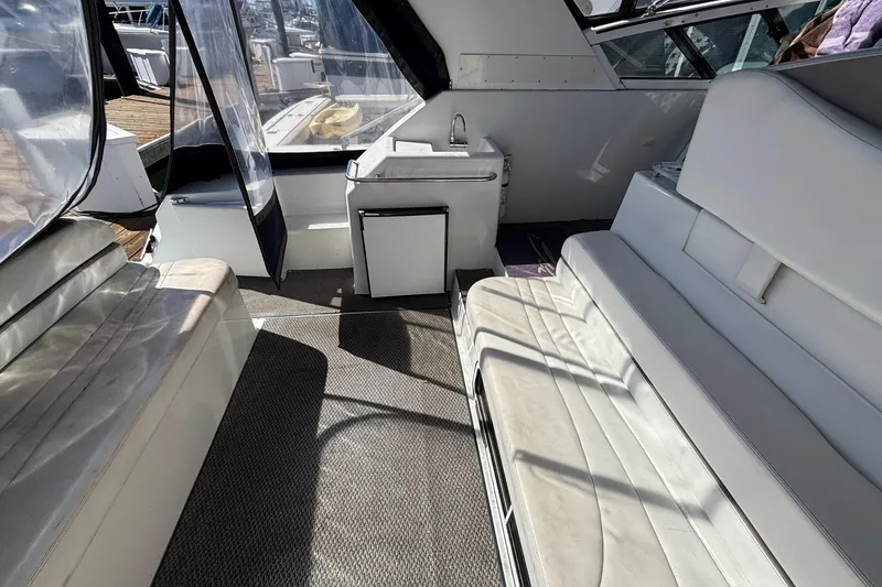 Slide: The Image of Interior of a 1998 Trojan 400 yacht with white seating and compact kitchenette. - 10