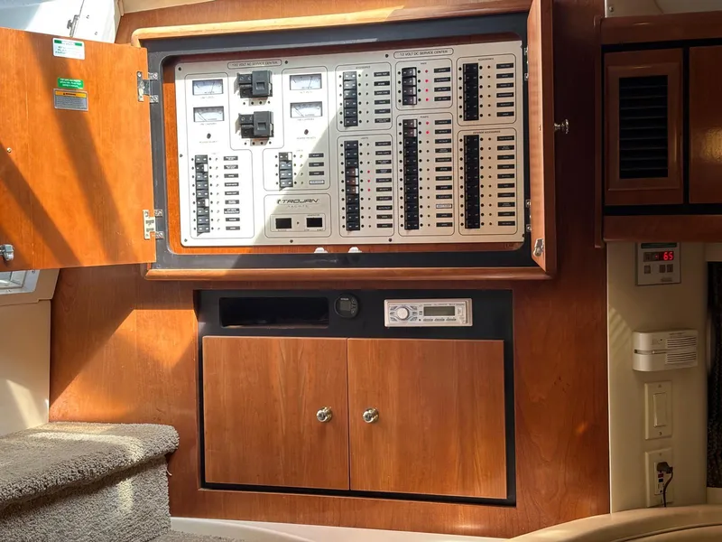 Slide: The Image of Electrical panel inside a 1998 Trojan 400 boat, featuring wooden cabinetry and control switches. - 12