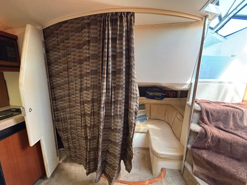 Slide: The Image of Interior of a 1998 Trojan 400 boat with a cozy seating area and privacy curtain. - 17