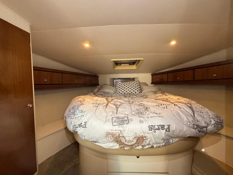 Slide: The Image of 1998 Trojan 400 boat cabin with cozy bed, wooden cabinets, and soft lighting. - 19
