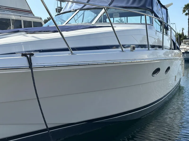 Slide: The Image of 1998 Trojan 400 boat docked, featuring sleek design and blue canopy. - 2