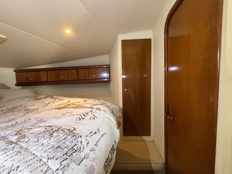 Slide: The Image of Cozy cabin interior of a 1998 Trojan 400 boat with wooden accents and a comfortable bed. - 20