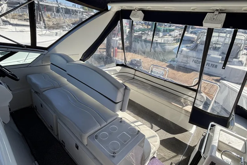 Slide: The Image of Interior of a 1998 Trojan 400 yacht with white seating and marina view. - 8