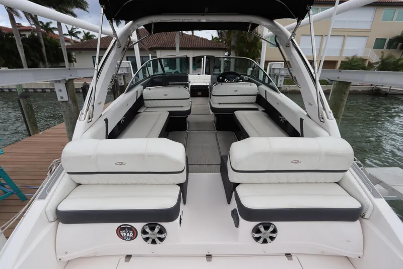 Slide: The Image of 2018 Regal 29 OBX boat interior with white seating, docked by waterfront homes. - 12