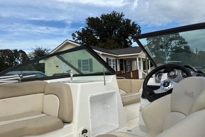 Slide: The Image of 2022 NauticStar 203 DC boat interior with beige seating, steering wheel, and dashboard. - 10