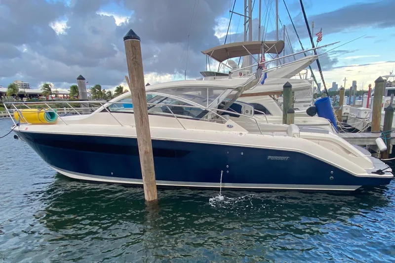 The Image of 2014 Pursuit SC 365i Sport Coupe docked at marina, calm waters, cloudy sky. - 0