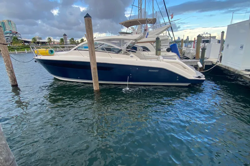 Slide: The Image of 2014 Pursuit SC 365i Sport Coupe docked, featuring deck and rolled yellow mat. - 13