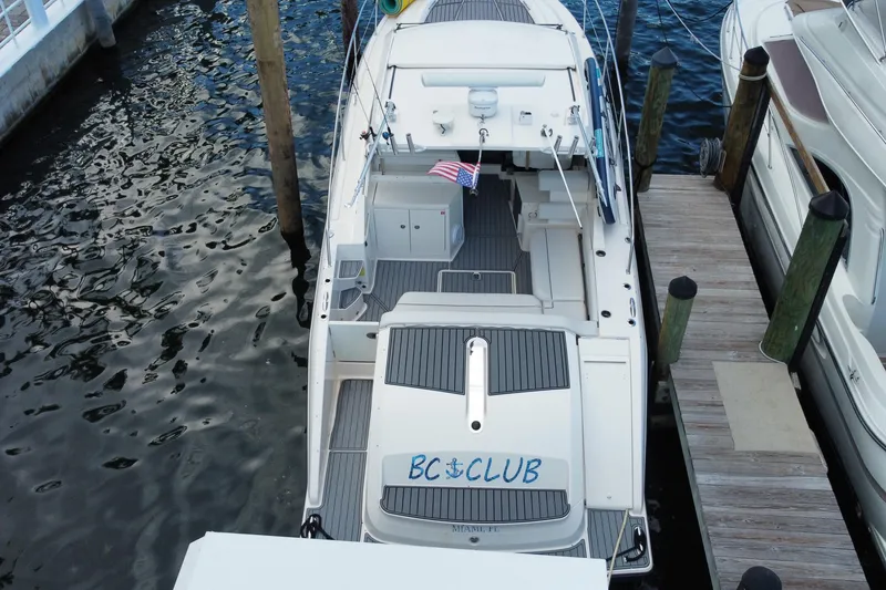 Slide: The Image of 2014 Pursuit SC 365i Sport Coupe boat with "BC Club" logo, docked with storage compartment open. - 18